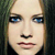 Pixelated close-up of a person's face with light skin, blue eyes, and dark hair against a dark background.