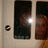 A static image shows a dark interior with two figures, one holding a bright light source, against a light-colored wall with a circular object on the left.