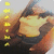 Animated sequence showing a character in yellow top and dark pants holding an object, with vertical text on left side.