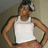 Pixelated image of a person wearing a white tank top and orange shorts, standing with hands on hips against a muted background.