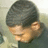 Pixelated close-up of a person with short dark hair, light skin tone, and visible ear against muted background.