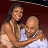 Two people embrace in a close-up pose against a dark red background with faint pixelated patterns.