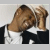 Static 50x50 pixel icon showing two cartoon-style figures in black suits with white shirts, one figure leaning toward the other's face as if whispering or kissing.