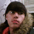Pixelated static image of a person with dark hair and light skin wearing red clothing against a blurred background.
