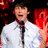 Four distinct views of a person with curly hair in different outfits and settings, including white shirt/tie, patterned top, dark jacket, and drum set background.