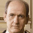 Static 48x48 pixel icon showing a close-up of a man's face with light skin, dark hair, and formal attire against a neutral background.