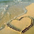 Pixelated image of a heart-shaped object with dark brown border on light beige background, surrounded by blurred green and blue tones.