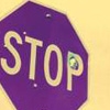 Purple octagonal sign with yellow border displaying 'STOP' in large yellow letters, one letter partially obscured by a small green and blue pixel cluster.