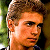Pixelated close-up of a person's face with brown hair and light skin tone, set against blurred green background elements.