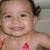 Pixelated close-up of a child's face with dark hair tied back, wearing a light-colored top with pink and yellow details.