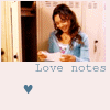 A woman with long brown hair in a light blue cardigan reads a paper in front of lockers, with 'Love notes' text and a heart symbol below.