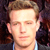 Static pixelated image of a person's face with light brown hair and neutral expression against dark background.