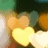 A pixelated static image shows a bright yellow heart shape with orange accents, surrounded by blurred green and brown background elements.