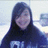 A person with long dark hair wearing a dark hoodie with white text, smiling in front of an indoor background.
