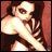 Pixelated image of a person with dark hair, light skin, and a white top against a reddish-brown background.