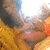 A pixelated image of a person with dark hair and light skin, wearing an orange garment against a yellow background.