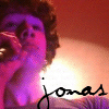 Pixelated image of a person with curly hair holding a microphone, with the name 'Jones' written in cursive script below.