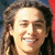 A person with long curly hair smiling, displayed in a of four showing slight variations