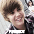 A person with light brown hair and a dark plaid shirt smiles broadly in a pixelated image with a white background and partially obscured text below.