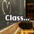 A pixelated animation of a classroom scene with a chalkboard, desks, and a heart drawing that breaks apart, accompanied by text.
