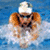 A pixelated image of a swimmer in a pool with blue water, wearing a white cap and dark goggles, with a yellow banner reading SWIMMING above and a yellow equal sign below.