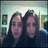 Two people with dark hair pose closely together in a pixelated image, wearing dark clothing against a light background.