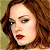 Static pixelated image of a woman's face with brown hair, red lips, and light skin tone against a muted background.