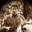 Static pixelated image of a person with brown hair and light skin tone, rendered in low-resolution grayscale tones on a dark background.