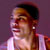 Pixelated static image of a person with dark hair and light skin wearing a white sleeveless top against a purple background.