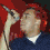 A person with red hair sings into a microphone across four showing head and hand movements