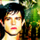Pixelated image of a person with dark hair and red lips against green foliage background, showing slight color variation