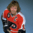 Pixelated image of a person in red and white hockey jersey with black accents, holding a hockey stick against light blue background; orange text 'Stanley Cup Champs' below.
