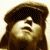 Pixelated image of a person with long hair wearing a dark cap, next to text reading 'marc broussard .com' on a brown background.