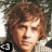 Pixelated portrait of a person with curly brown hair, light skin tone, and closed eyes against a blurred background.