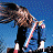 Animated contact sheet showing two frames of a person with long brown hair playing an electric guitar against a blue background.