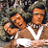 Two pixelated figures in a brown and white outfit with green foliage background, next to green text on dark green.