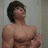 Static pixelated image of a shirtless person with dark hair, standing against a light gray background with a slightly blurred effect.