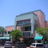 Pixelated static image of a building with greenery under a light blue sky, showing indistinct architectural details and color blocks.