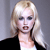 Pixelated image of a person with long blonde hair wearing a black jacket over a white top against a gray background.