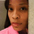 A pixelated close-up of a person with long dark hair wearing a pink top against a neutral background.