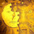 A pixelated yellow figure with a rounded head and simple limbs stands against a warm-toned gradient background of orange and brown hues.