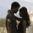 Two mirrored pairs of silhouetted figures standing on a beach at sunset, each pair embracing with one figure holding the other's face.