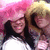 Two people with pink and yellow hair under a large pink fluffy hat, smiling in close proximity.