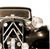 A pixelated static image shows a dark vehicle with a light-colored grille and headlights, viewed from a low angle against a white background.