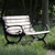 Pixelated image of a white park bench with dark metal armrests and legs, set against a blurred green and dark background.