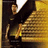 Pixelated image of a person in dark clothing holding a golden object against a gradient background.