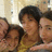 Three people pose closely together in a pixelated image with warm tones and soft lighting, one wearing a yellow top.