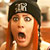 Static pixelated image of a person with red hair wearing a black headband, mouth open in an exaggerated expression against a blurred background.