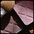 Pixelated image of a figure in dark clothing with light-colored hair against a gradient background of brown and pink tones.