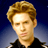 Static pixelated image of a person with light brown hair and dark clothing against a blue gradient background.